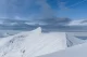 Snowy mountain peak under a blue sky with scattered clouds