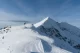 Two hikers approaching a sharp, snowy summit