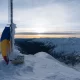 Frozen Romanian flag at Moldoveanu Peak during sunset