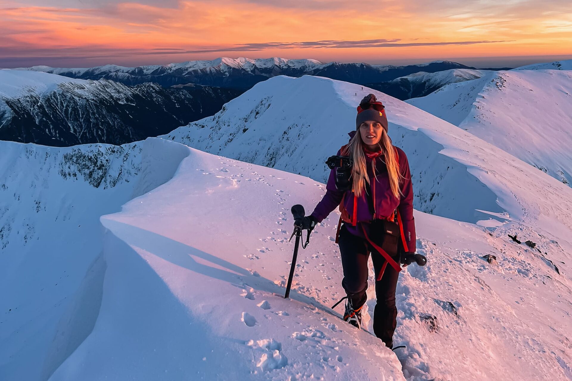 Hiker on a snowy ridge at sunset on Moldoveanu Peak