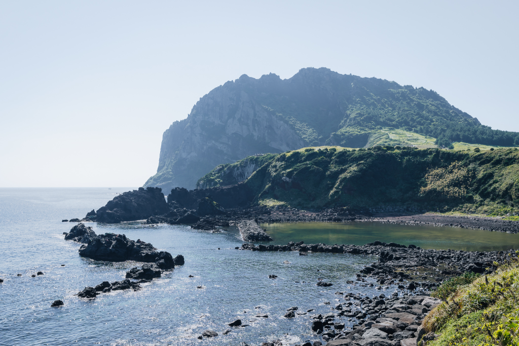 Rocky shoreline leading to Seongsan Ilchulbong’s cliffs