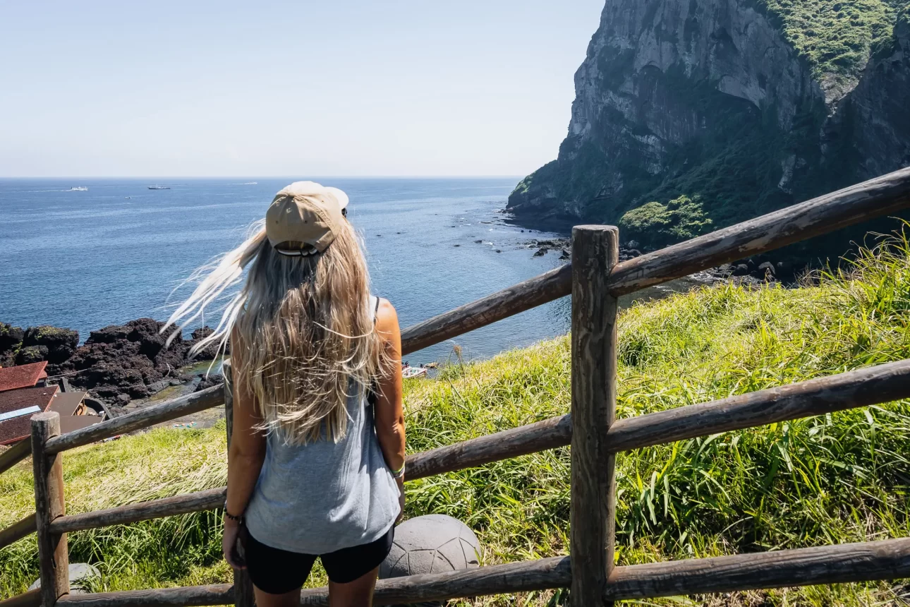 Woman facing Seongsan Ilchulbong’s coastline