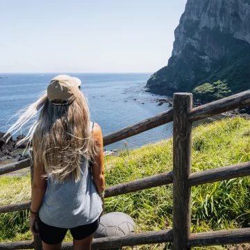 Woman facing Seongsan Ilchulbong’s coastline